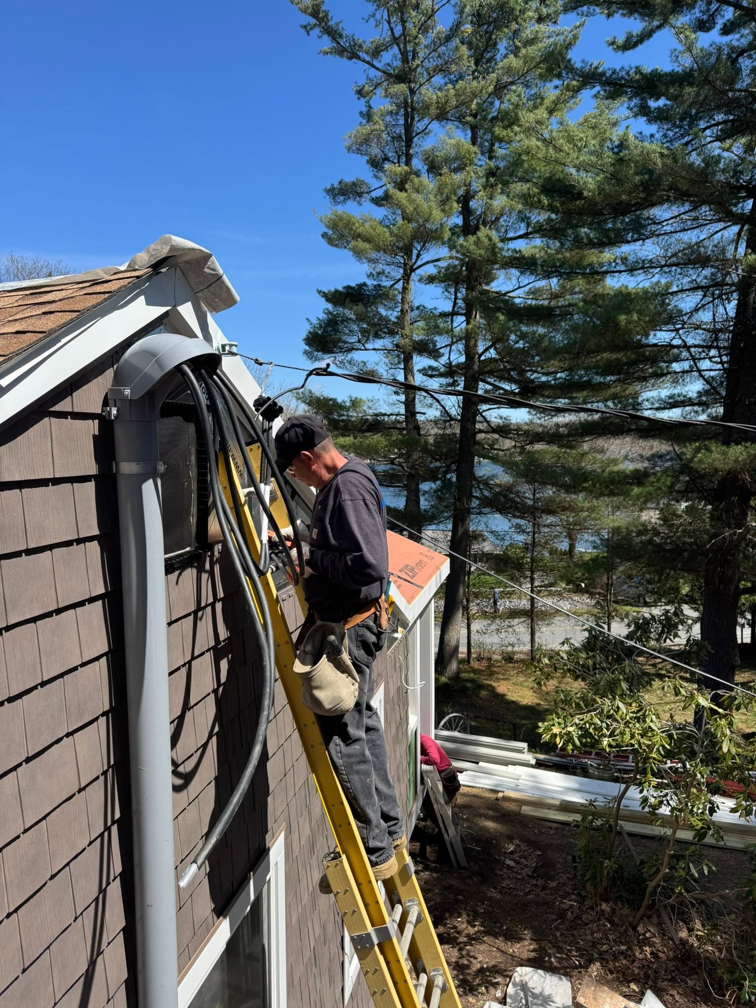 Tower Electric crew member installing an electrical service mast on a Berkshire County home