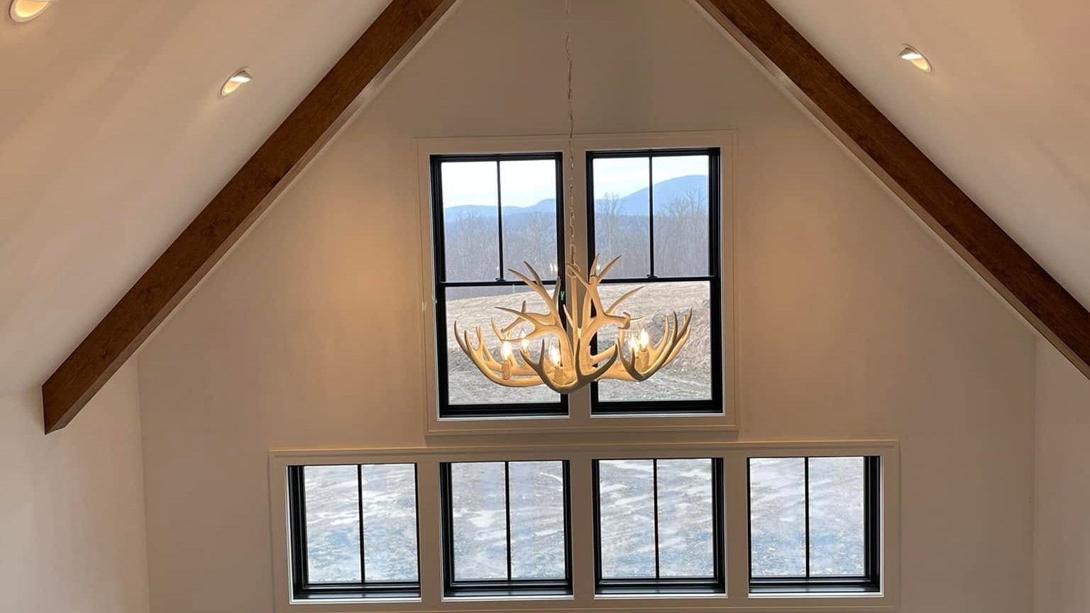 Antler chandelier installed beneath a peaked window overlooking the Berkshire mountains
